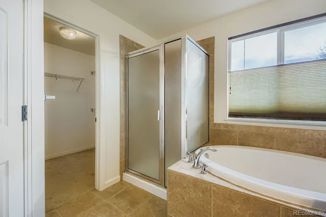 a bathroom with a tub a mirror and a shower