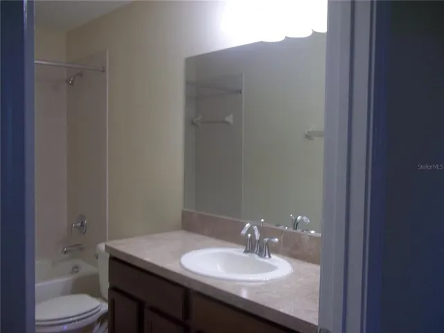a bathroom with a granite countertop sink toilet a mirror and shower