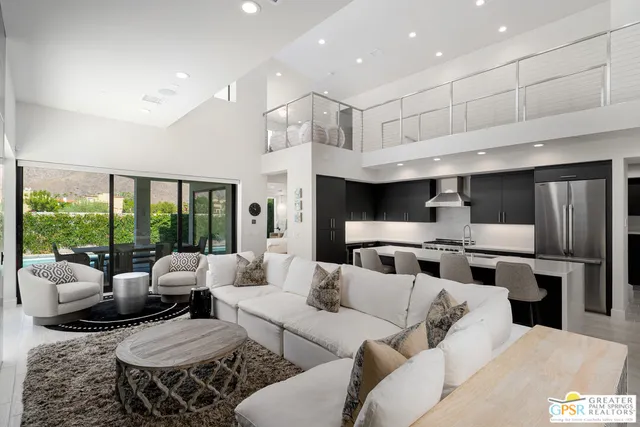 a living room with furniture kitchen view and a large window