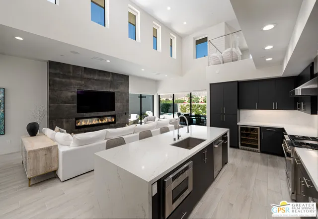 a large living room with stainless steel appliances kitchen island granite countertop a stove and a flat screen tv