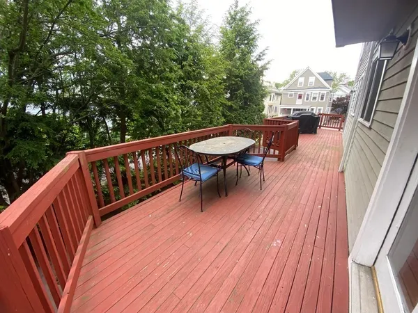a balcony with wooden floor table and chairs