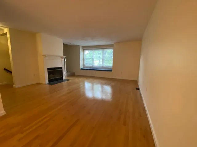 a view of a livingroom with wooden floor and a fireplace