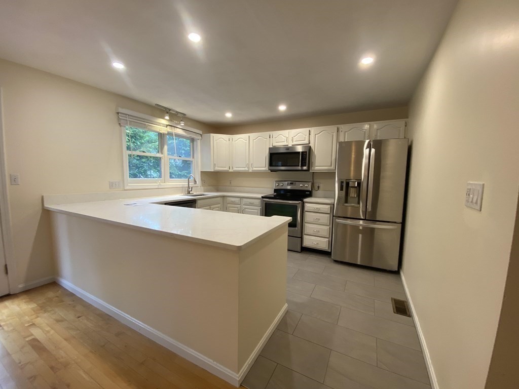 1047 Washington Street, Unit 2 Newton, MA 02465 - Photo 5 of 20 a kitchen with kitchen island a counter top space cabinets stainless steel appliances and a window