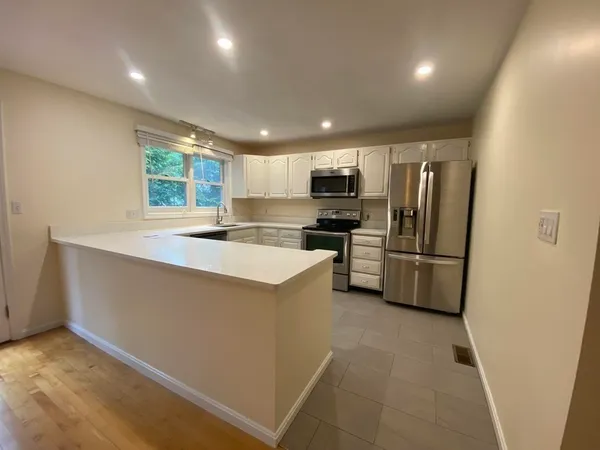 a kitchen with kitchen island a counter top space cabinets stainless steel appliances and a window