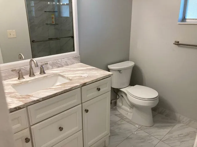 a bathroom with a granite countertop toilet and a sink