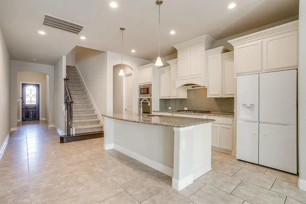 a kitchen with stainless steel appliances granite countertop a refrigerator a sink and a stove