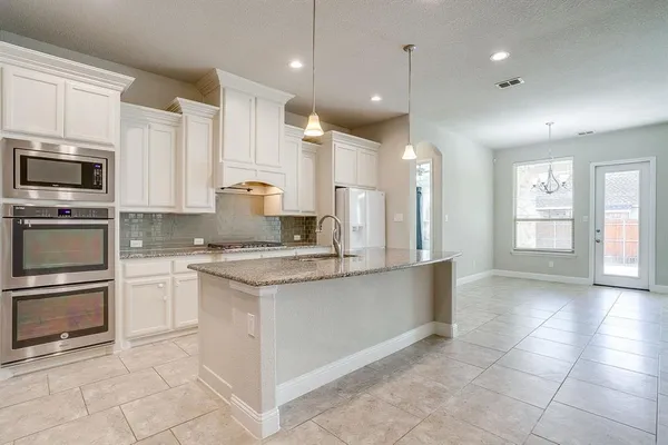 a kitchen with kitchen island granite countertop a stove sink and microwave