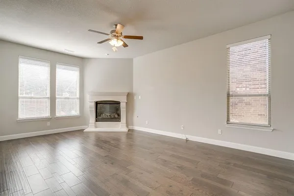 an empty room with wooden floor chandelier and windows
