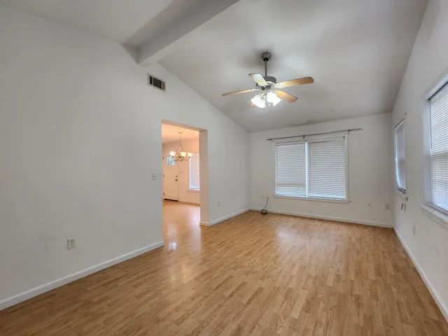 a view of empty room with wooden floor and fan