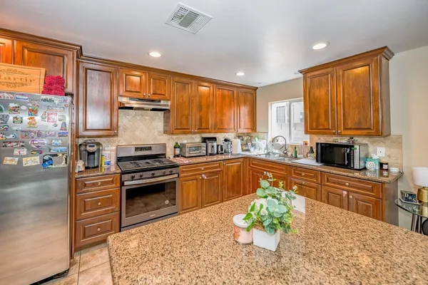 a kitchen with stainless steel appliances granite countertop a stove a sink dishwasher a microwave oven and a dining table with wooden cabinet