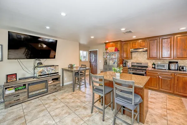 a kitchen with stainless steel appliances a stove a sink a oven a dining table and chairs