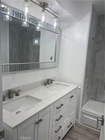 a bathroom with a sink vanity granite tub shower and a mirror