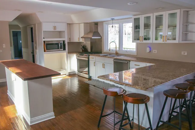 a kitchen with stainless steel appliances granite countertop a stove top oven a sink a dining table and chairs