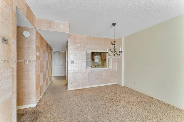 a view of a livingroom with a chandelier fan and refrigerator