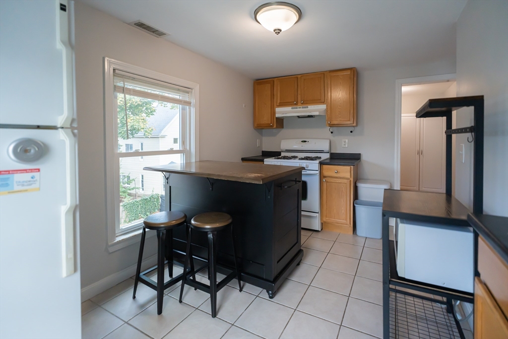 131 Summer Street, Unit 2 Somerville, MA 02143 - Photo 1 of 15 a kitchen with stainless steel appliances granite countertop a stove a refrigerator a sink a dining table and chairs with wooden floor