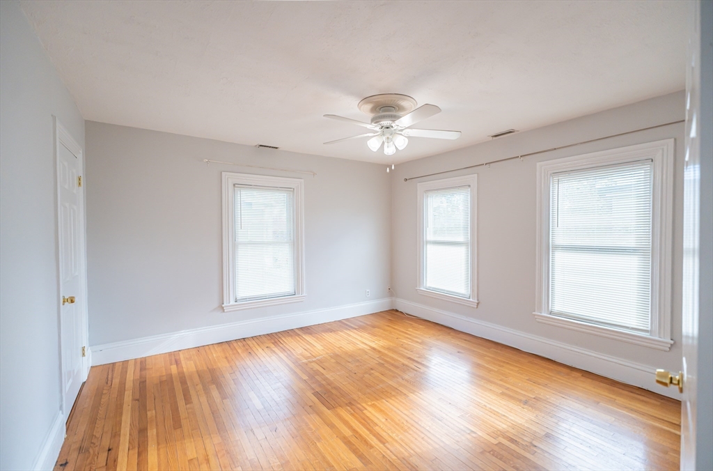 131 Summer Street, Unit 2 Somerville, MA 02143 - Photo 3 of 15 an empty room with wooden floor and windows