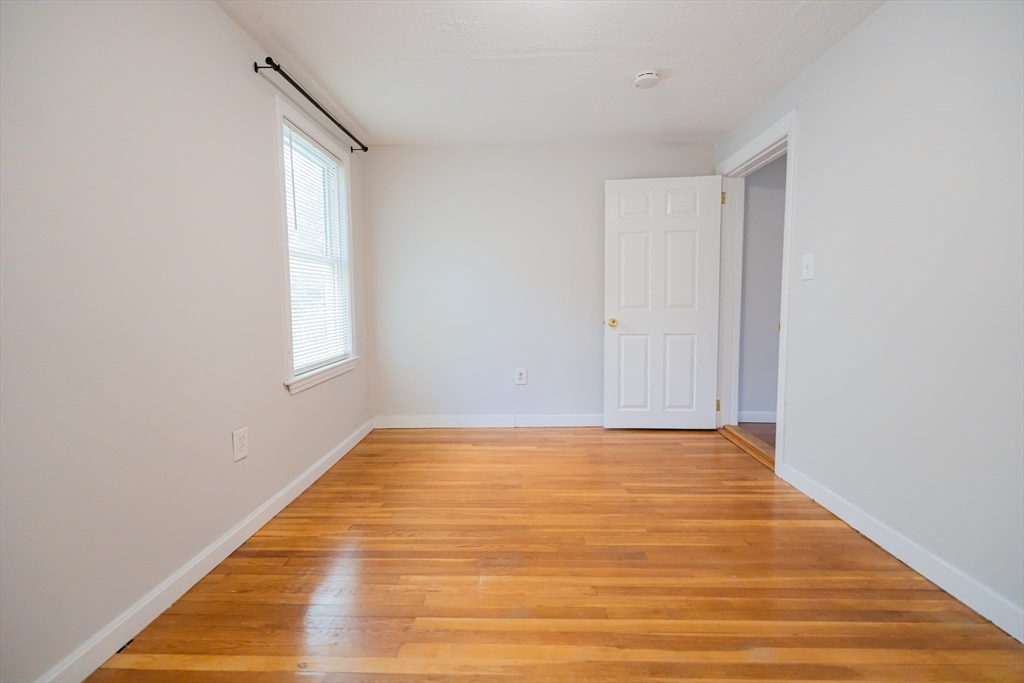 131 Summer Street, Unit 2 Somerville, MA 02143 - Photo 8 of 15 a view of an empty room with wooden floor and a window