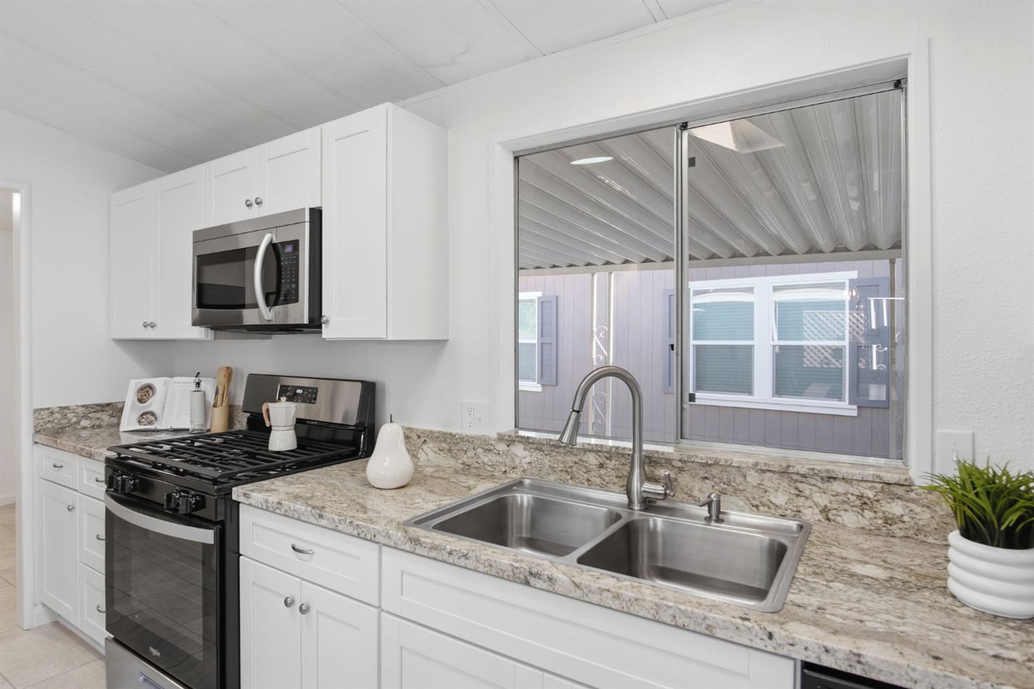 1428 Playground Way Modesto, CA 95355 - Photo 6 of 29 a kitchen with granite countertop a sink and a microwave