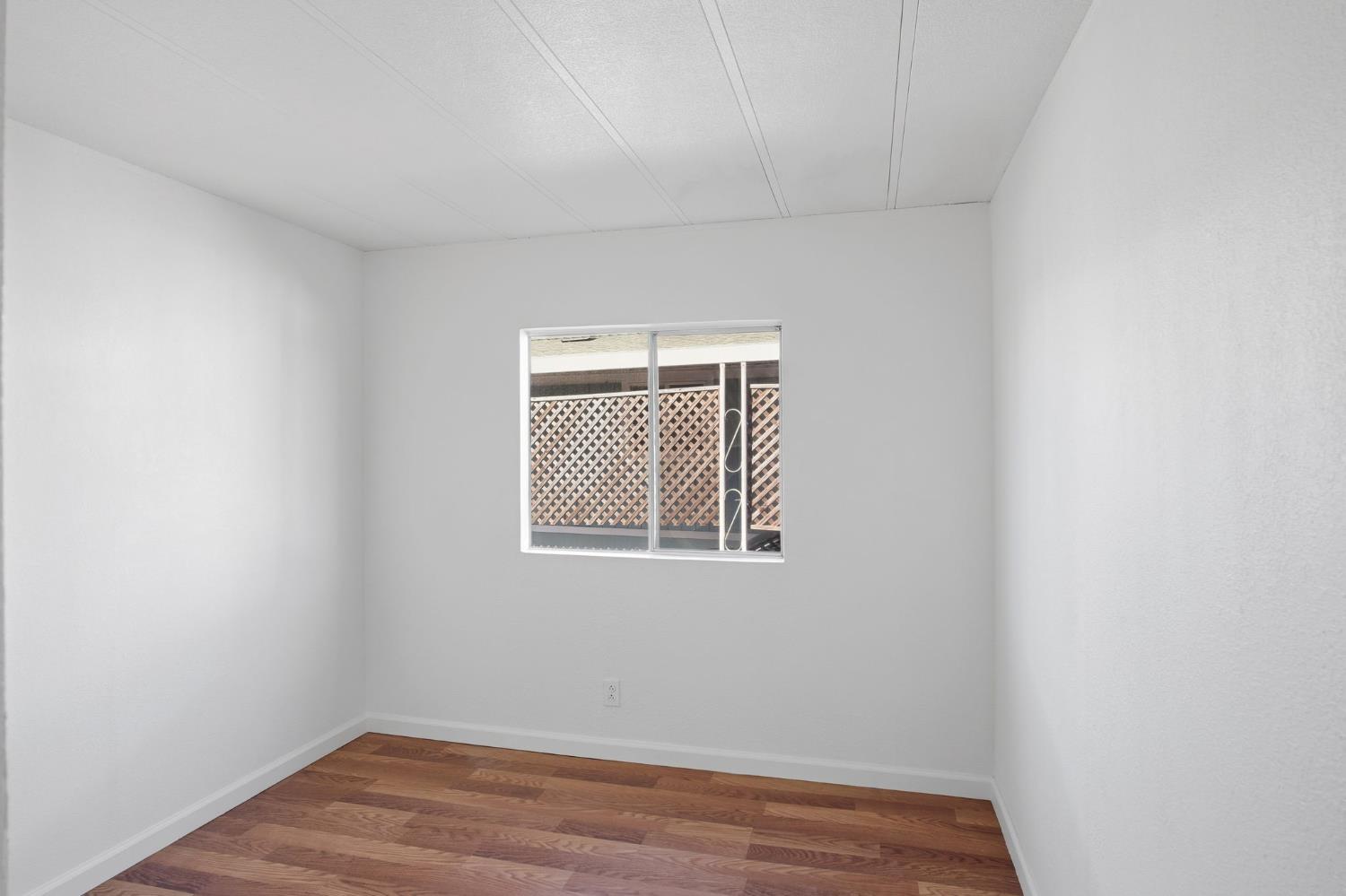 1428 Playground Way Modesto, CA 95355 - Photo 8 of 29 a view of an empty room with wooden floor and a window
