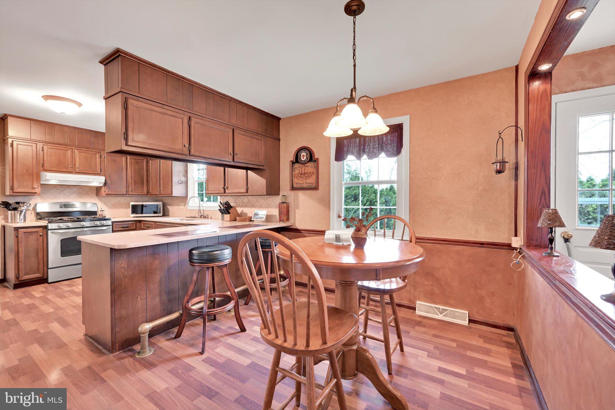 1546 Singer Road Wyomissing, PA 19610 - Photo 4 of 40 a kitchen with stainless steel appliances granite countertop a stove a sink dishwasher a dining table and chairs with wooden floor