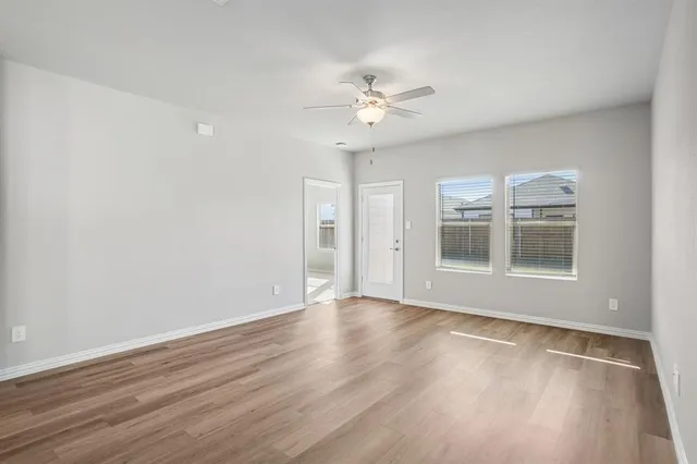 a view of an empty room with a window and wooden floor