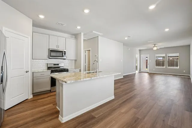 a kitchen with stainless steel appliances granite countertop a stove top oven a sink and a refrigerator