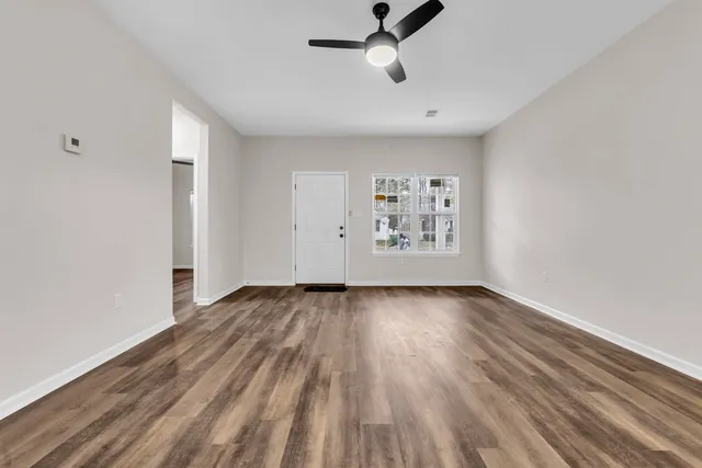 a view of an empty room with wooden floor and a window