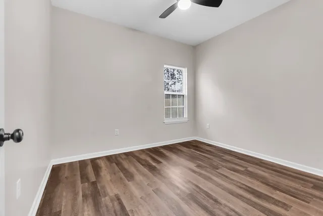 a view of an empty room with wooden floor and a window