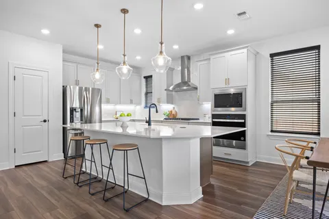 a kitchen with stainless steel appliances kitchen island a refrigerator and a wooden floors