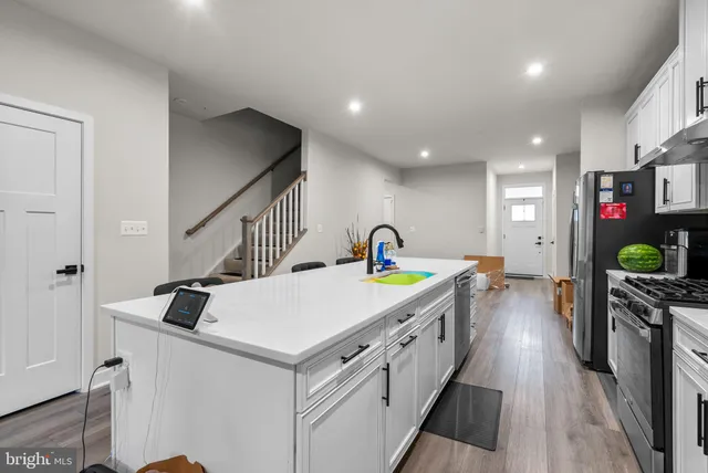 a kitchen with a sink a stove a refrigerator and white cabinets with wooden floor