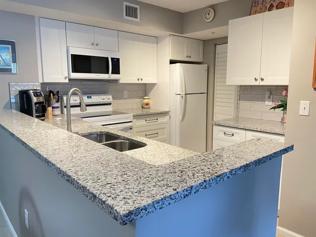 a kitchen with stainless steel appliances granite countertop a sink refrigerator and microwave