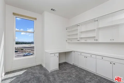 a kitchen with white cabinets and window