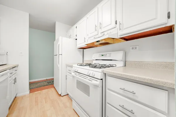 a kitchen with white cabinets and white appliances