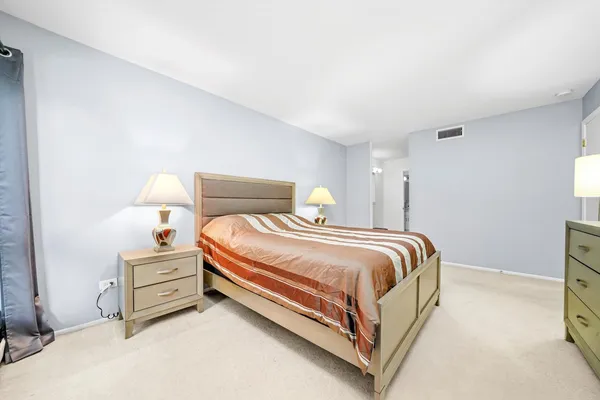 a bedroom with a bed and a lamp on dresser