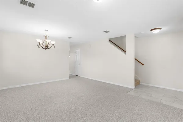 an empty room with chandelier fan and wooden floor