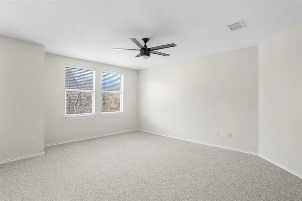 an empty room with a window and a fan