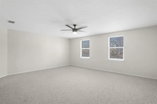 an empty room with windows and ceiling fan