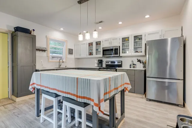 a kitchen with kitchen island a refrigerator a stove a microwave oven a sink with island and chairs with wooden floor