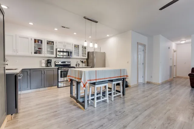a kitchen with stainless steel appliances a dining table chairs and wooden floor