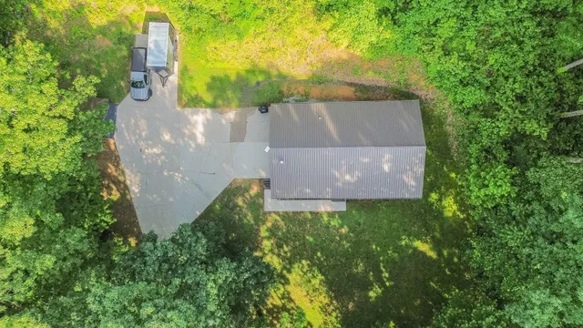 an aerial view of residential house with outdoor space and trees all around