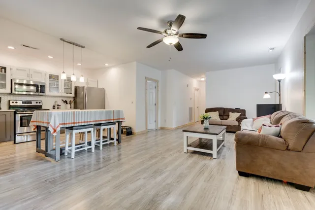 a living room with furniture wooden floor and a kitchen view