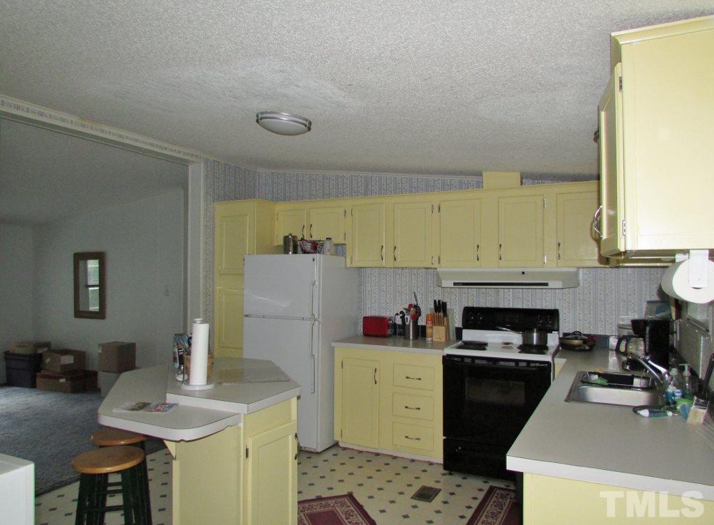 4128 Allensville Road Roxboro, NC 27574 - Photo 6 of 24 a kitchen with a sink a stove and refrigerator