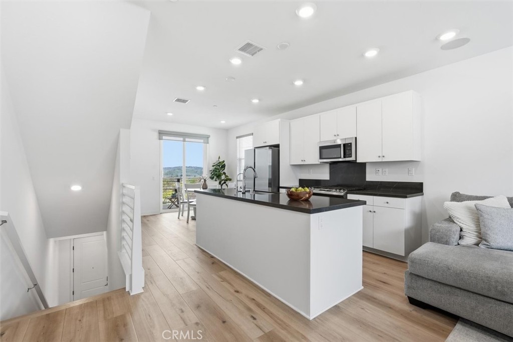 361 Gelding Way Rancho Mission Viejo, CA 92694 - Photo 15 of 59 a kitchen with stainless steel appliances kitchen island granite countertop a stove a sink a refrigerator and white cabinets with wooden floor