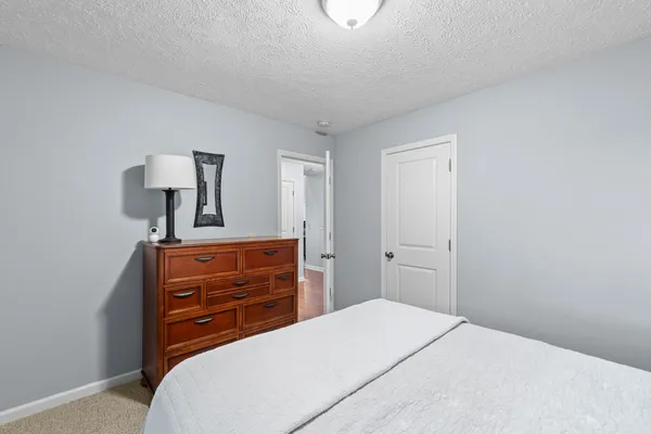 a bedroom with a bed and a lamp on dresser
