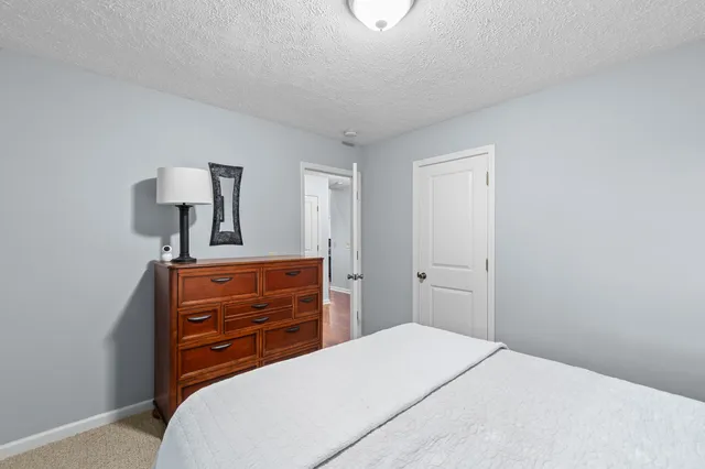 a bedroom with a bed and a lamp on dresser