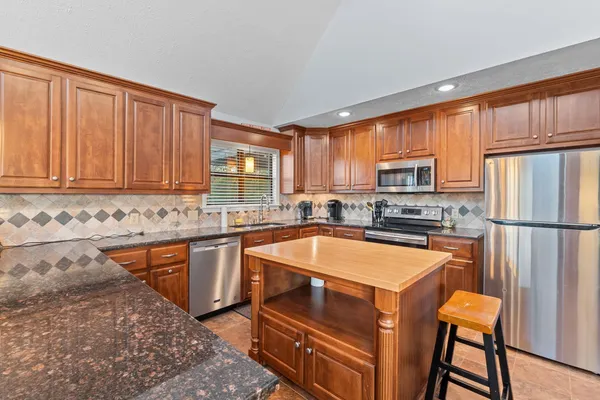 a kitchen with stainless steel appliances granite countertop a table chairs sink refrigerator and cabinets