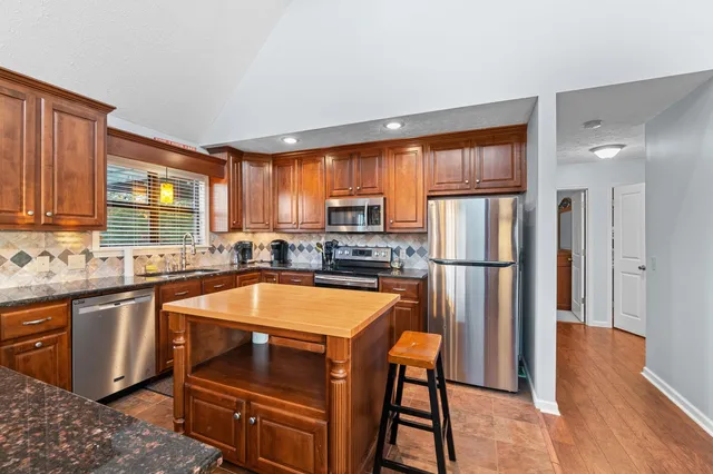 a kitchen with stainless steel appliances granite countertop a refrigerator a stove top oven a sink and dishwasher with wooden floor