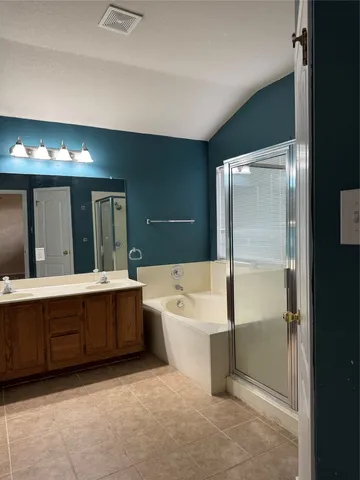 a spacious bathroom with a tub sink shower and mirror