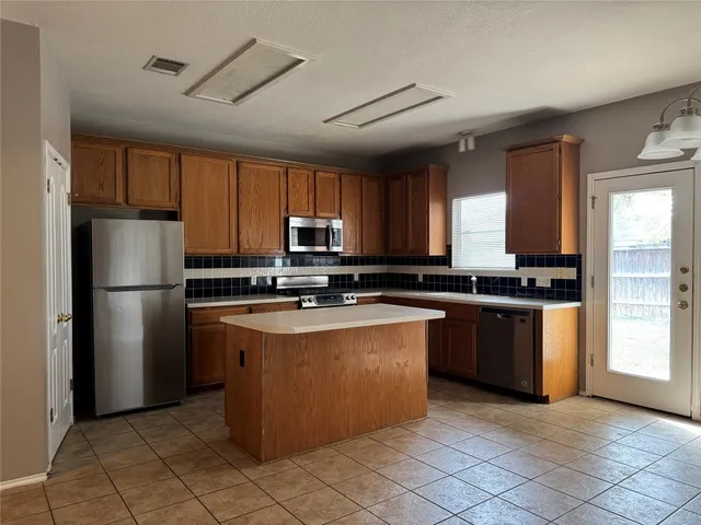 a kitchen with stainless steel appliances granite countertop a refrigerator a sink a stove a microwave and island