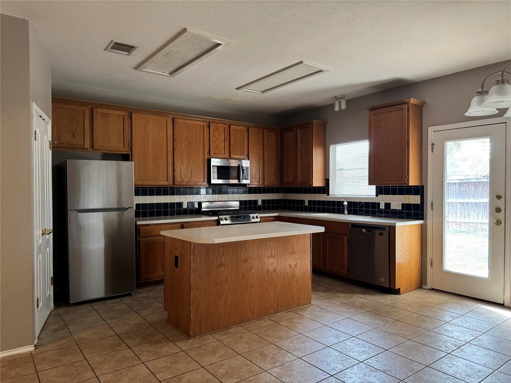 8724 Barrow Glen Loop Austin, TX 78749 - Photo 5 of 19 a kitchen with stainless steel appliances granite countertop a refrigerator a sink a stove a microwave and island